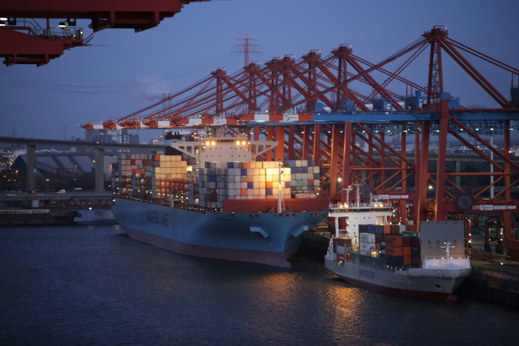 Container ship at port under red gantry cranes during loading operations