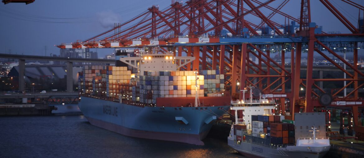 Container ship at port under red gantry cranes during loading operations