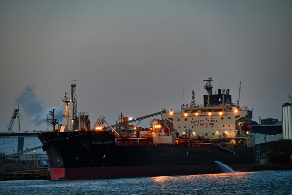 Cargo ship docked at port at night with industrial cranes