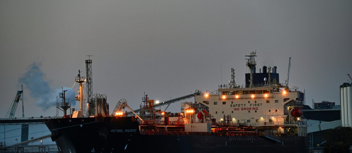 Cargo ship docked at port at night with industrial cranes