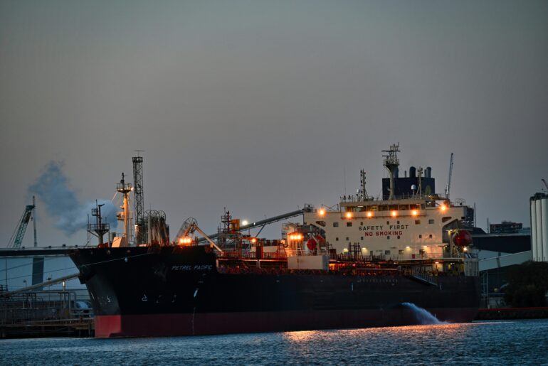 Cargo ship docked at port at night with industrial cranes