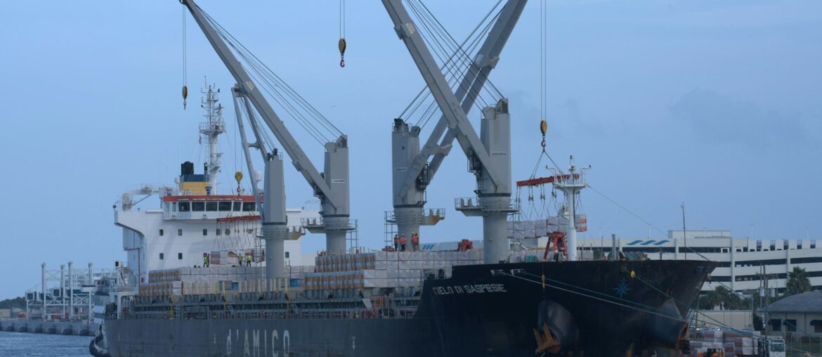 General cargo ship with deck cranes docked at a port berth