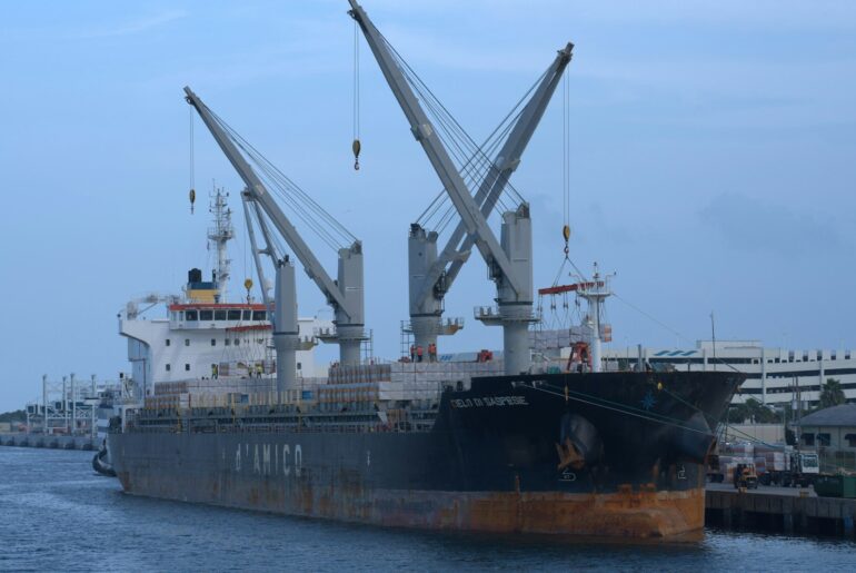 General cargo ship with deck cranes docked at a port berth